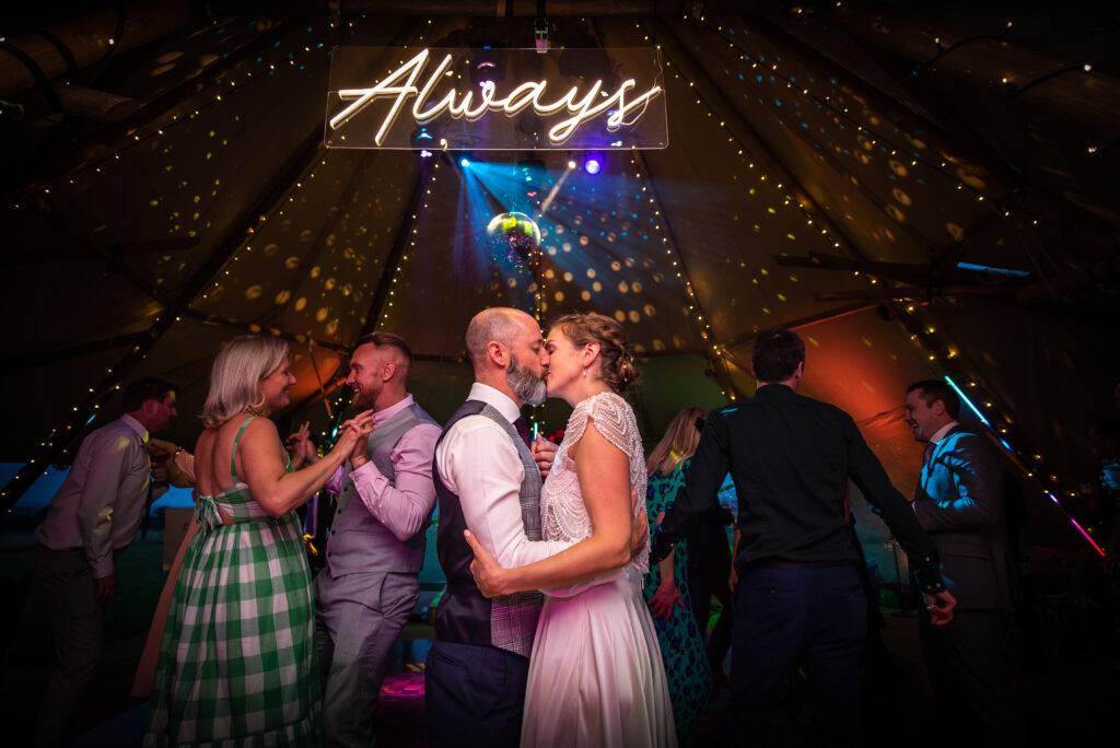 Couple standing under an always sign on the dancecfloor inside a tipi